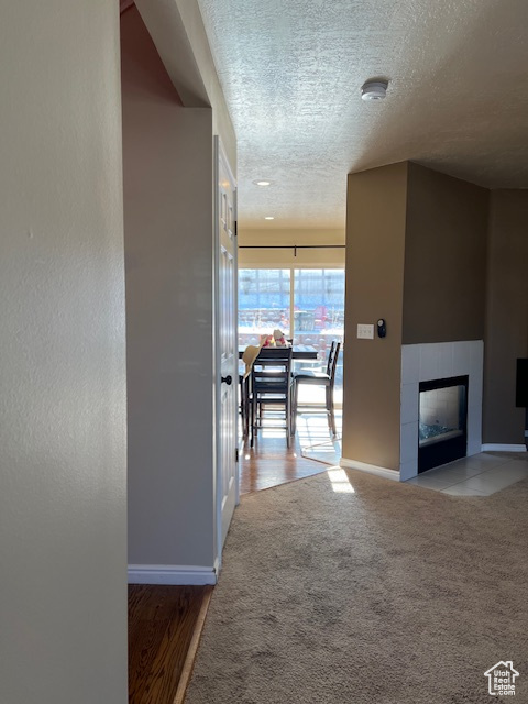 Corridor with a textured ceiling, baseboards, and carpet