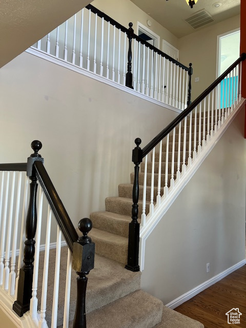 Stairway featuring wood finished floors, a towering ceiling, and baseboards