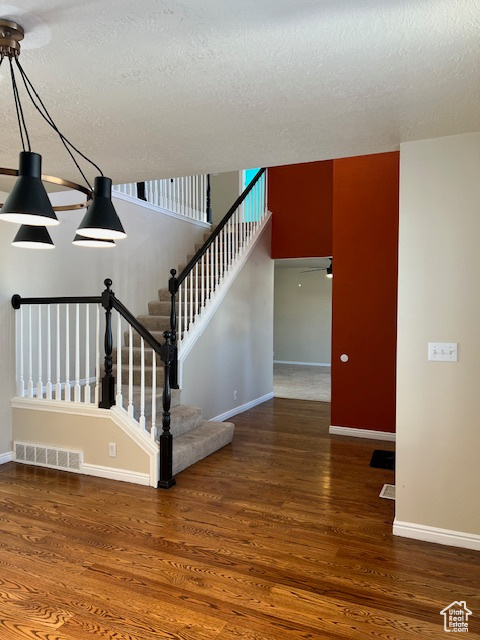 Stairway with baseboards, wood finished floors, and a textured ceiling