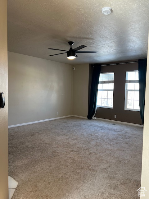 Spare room with a textured ceiling, a ceiling fan, baseboards, carpet flooring, and a smoke detector