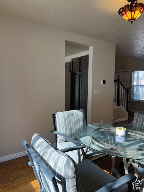 Dining room with a textured ceiling, wood finished floors, baseboards, and stairway