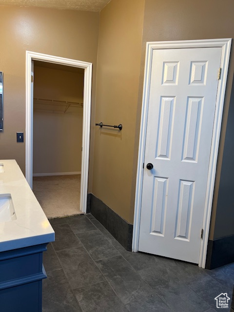 Bathroom with double vanity and a walk in closet