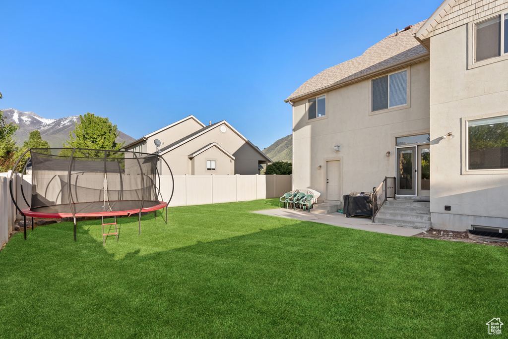 View of yard with a trampoline, a mountain view, entry steps, and a patio