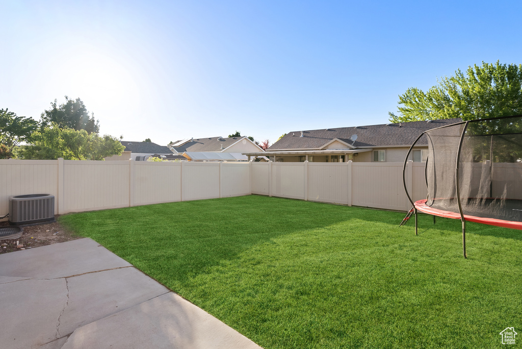 View of yard featuring central AC, a patio area, and a trampoline