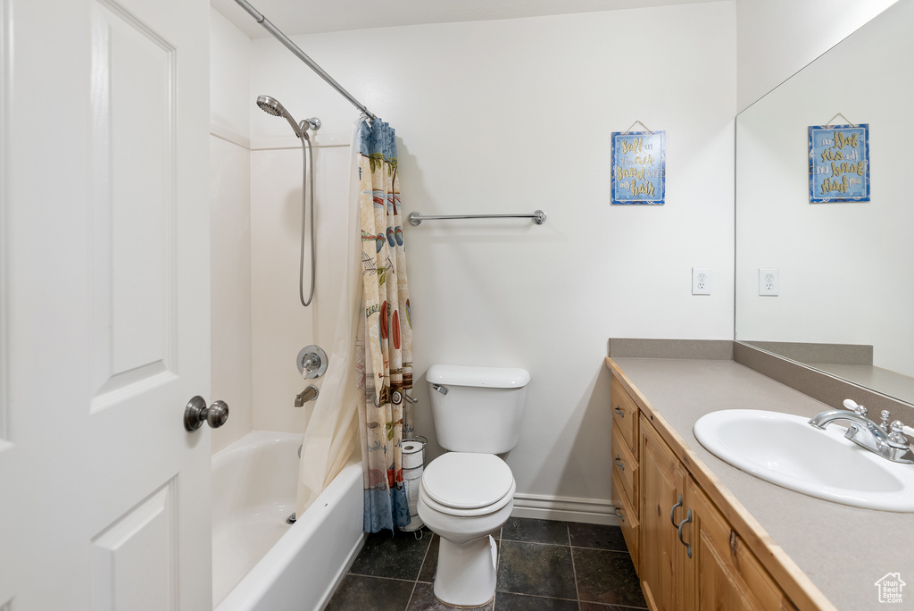 Bathroom with vanity, toilet, shower / tub combo, baseboards, and tile patterned flooring