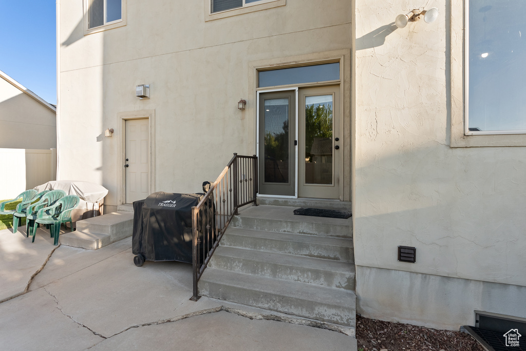 View of exterior entry with stucco siding and a patio
