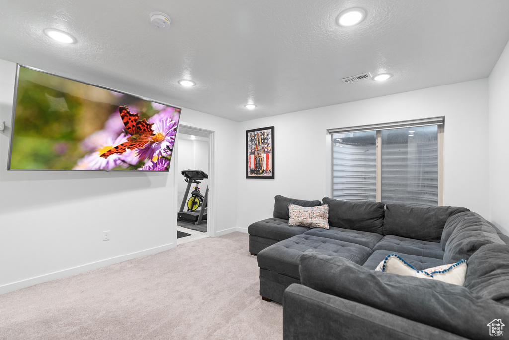 Carpeted living area with recessed lighting, baseboards, and a textured ceiling