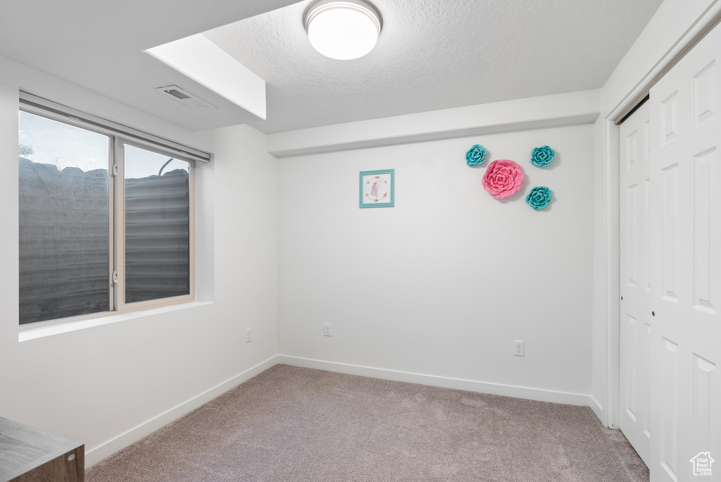 Unfurnished bedroom with carpet floors, a closet, baseboards, and a textured ceiling