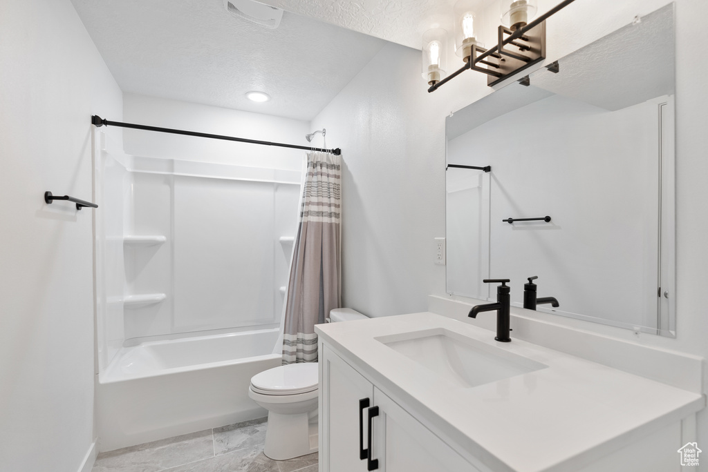 Bathroom featuring toilet, vanity, shower / tub combo with curtain, and a textured ceiling