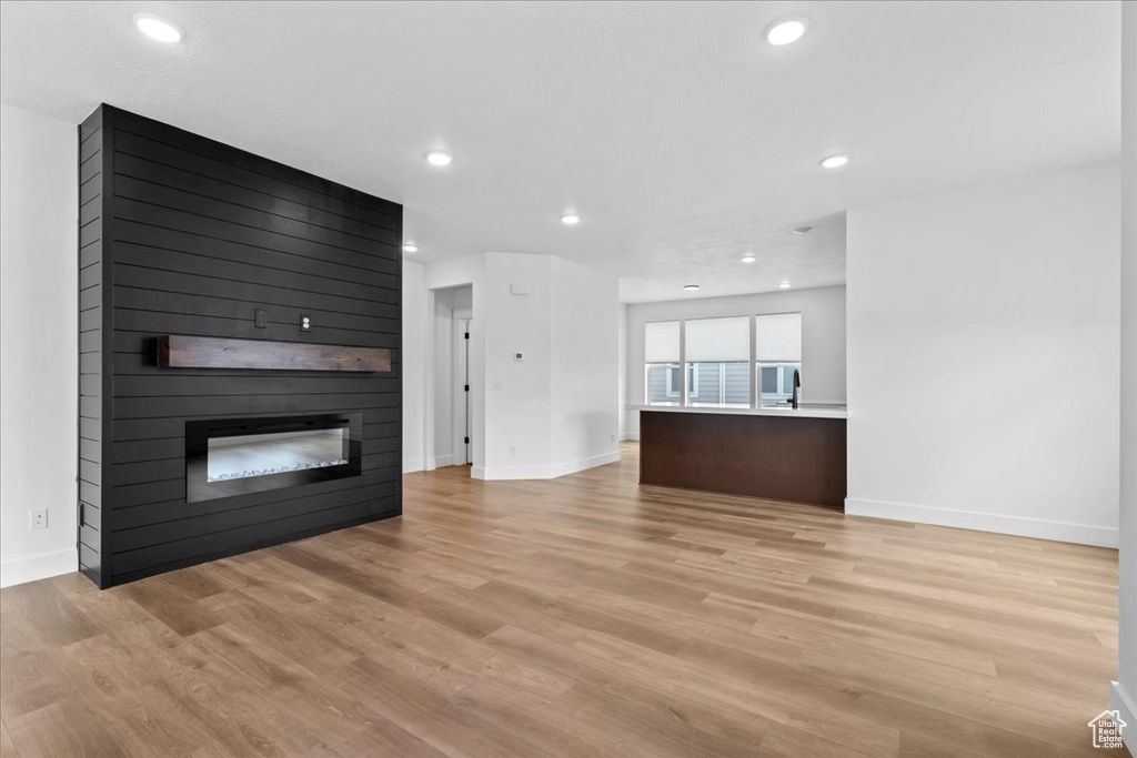 Unfurnished living room featuring a fireplace, baseboards, light wood-style flooring, and recessed lighting