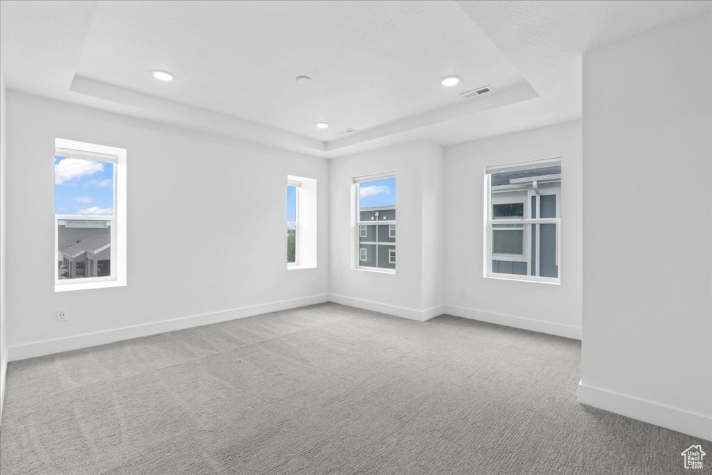 Carpeted spare room with a raised ceiling, recessed lighting, and baseboards