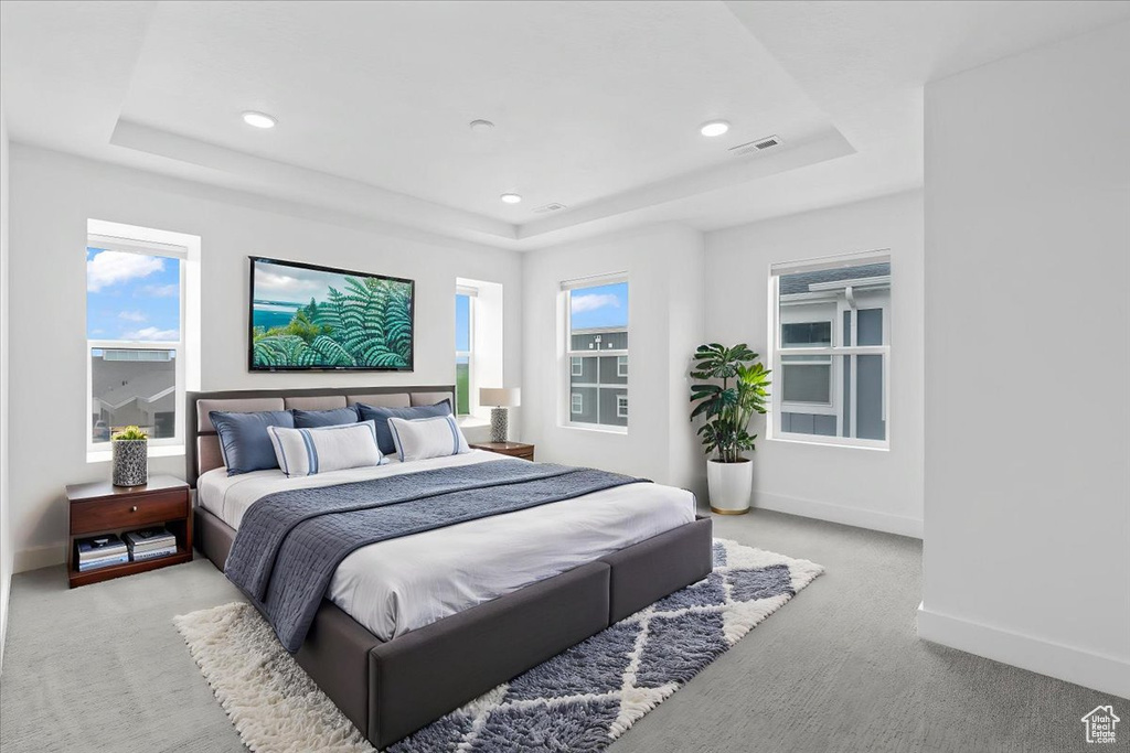 Bedroom featuring a tray ceiling, light carpet, recessed lighting, and baseboards