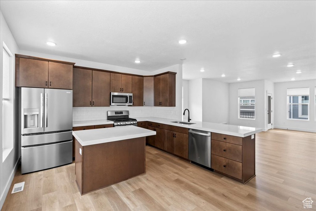 Kitchen featuring appliances with stainless steel finishes, backsplash, light wood-type flooring, light countertops, and recessed lighting