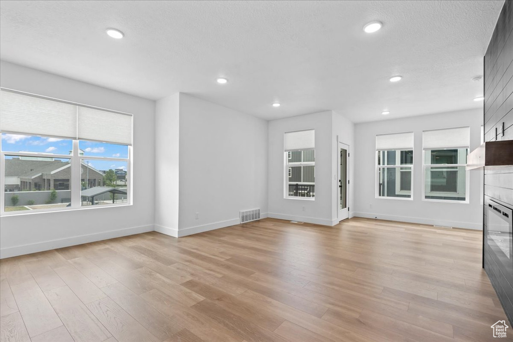 Unfurnished living room featuring healthy amount of natural light, light wood-style flooring, baseboards, and recessed lighting