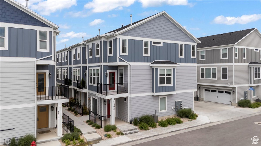 View of front facade featuring board and batten siding, an attached garage, and driveway