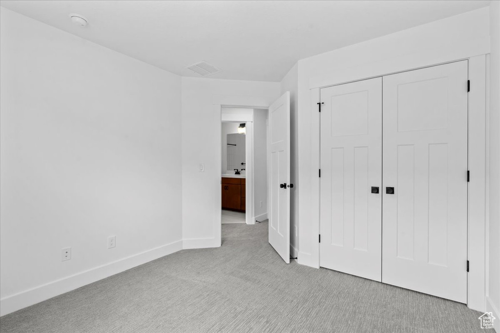 Unfurnished bedroom with light colored carpet, baseboards, and a closet