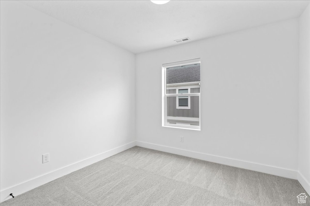 Empty room with light colored carpet and baseboards