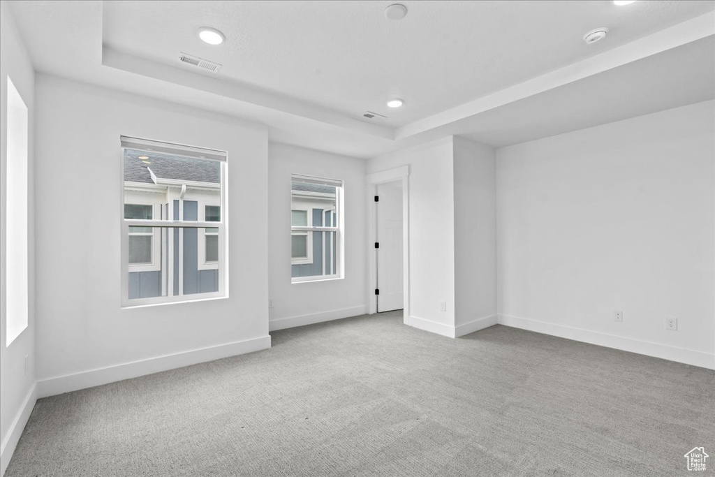 Spare room featuring a tray ceiling, carpet flooring, baseboards, a smoke detector, and recessed lighting
