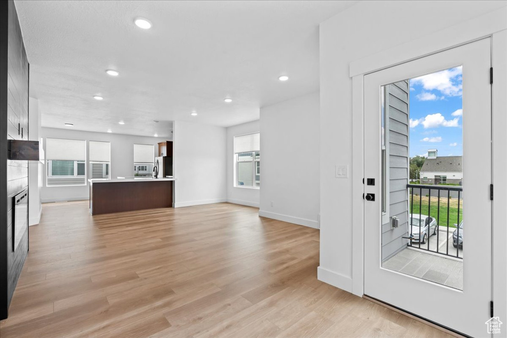 Unfurnished living room with light wood finished floors, recessed lighting, and baseboards