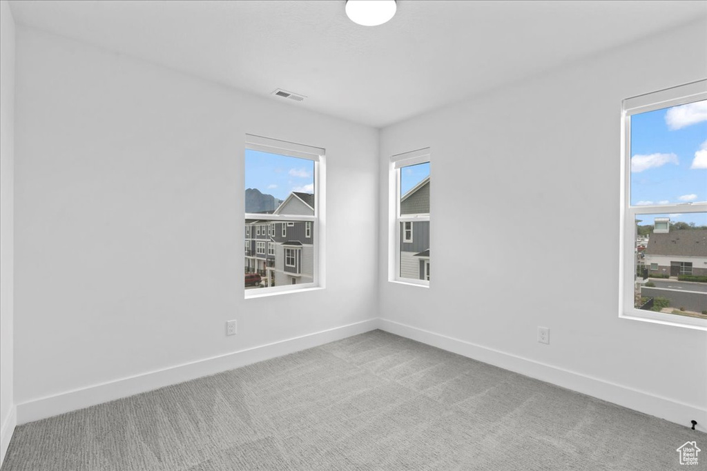 Carpeted empty room featuring baseboards and healthy amount of natural light