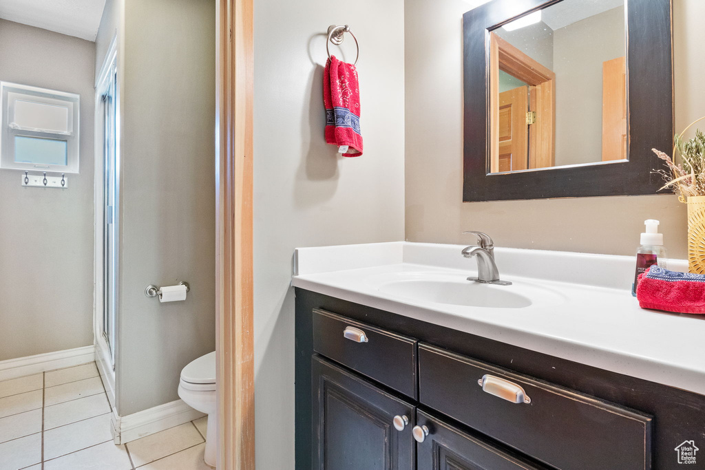 Bathroom with toilet, vanity, tile patterned flooring, a shower stall, and baseboards