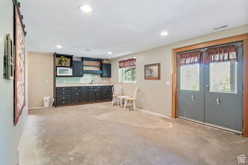 Unfurnished living room featuring unfinished concrete flooring, recessed lighting, and a sink