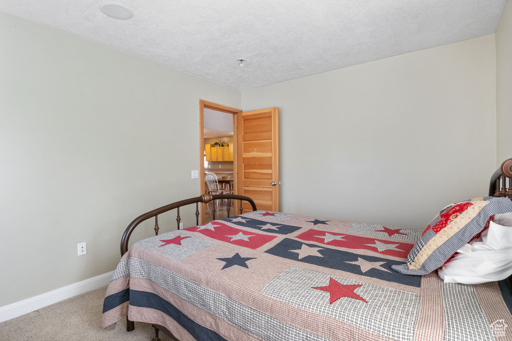 Carpeted bedroom featuring a textured ceiling and baseboards