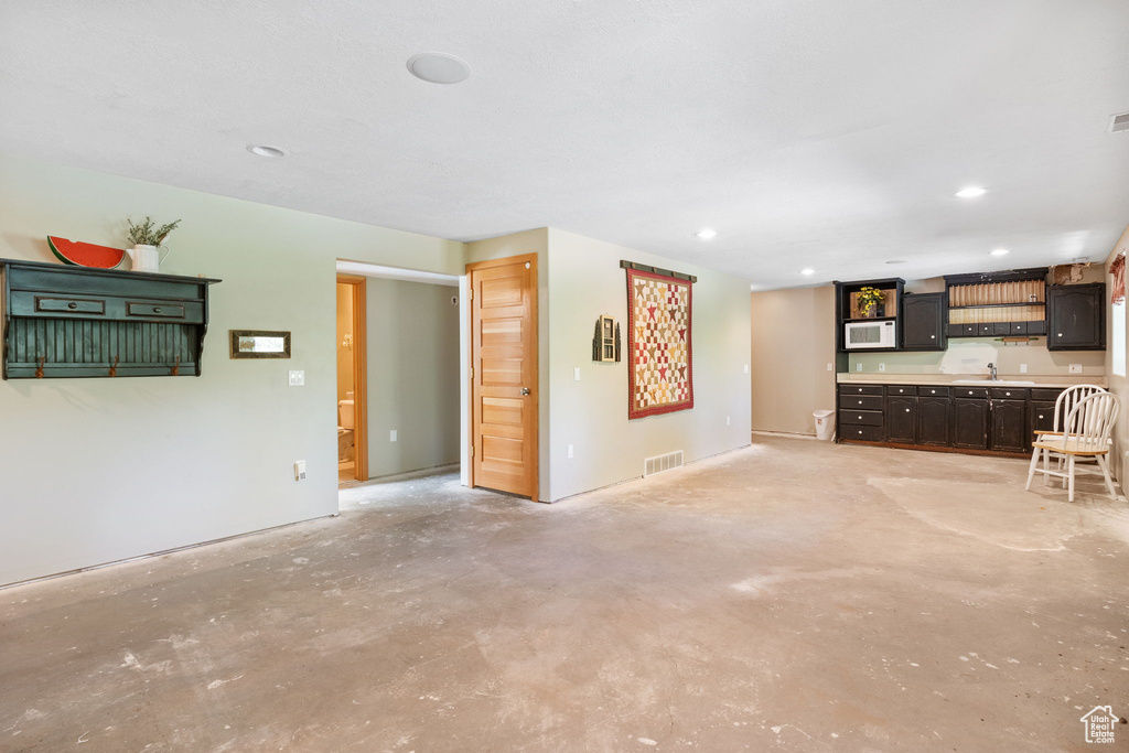 Unfurnished living room featuring a sink, concrete flooring, and recessed lighting