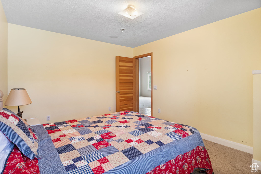 Bedroom with carpet, baseboards, and a textured ceiling