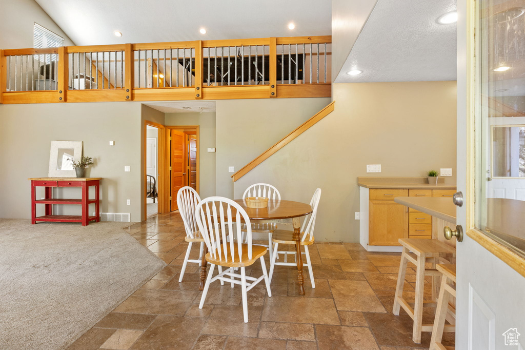 Dining area with stone tile floors, recessed lighting, and a high ceiling