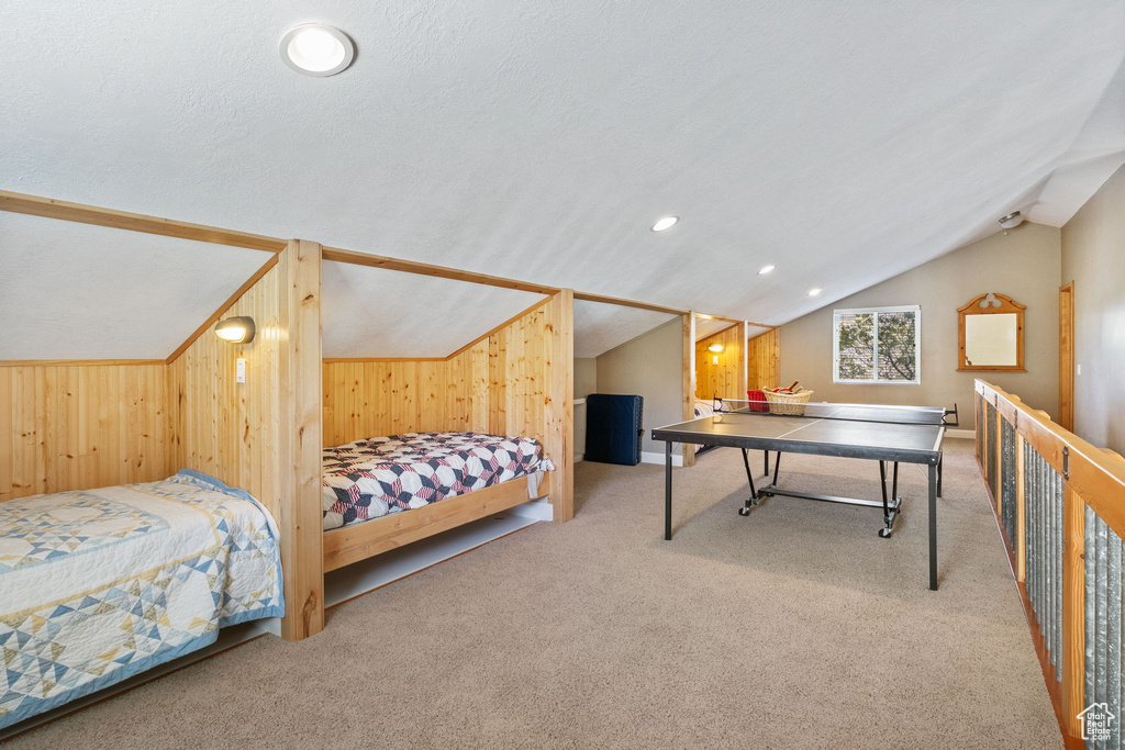 Bedroom featuring lofted ceiling, carpet floors, and wood walls