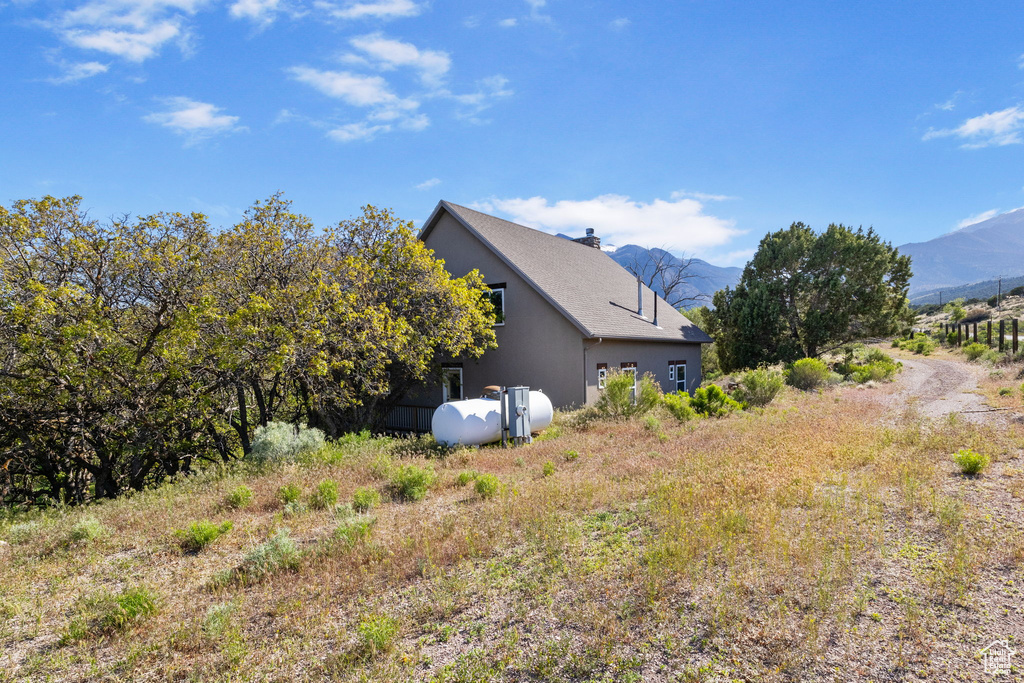 View of property exterior featuring a mountain view, stucco siding, and a chimney