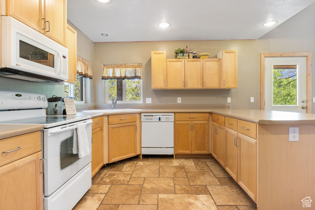 Kitchen with white appliances, light brown cabinetry, a sink, a peninsula, and recessed lighting