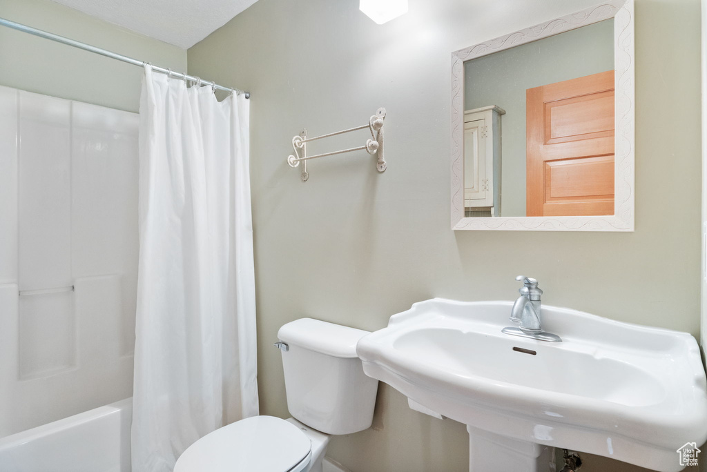 Full bathroom featuring toilet, a sink, and shower / bath combo with shower curtain