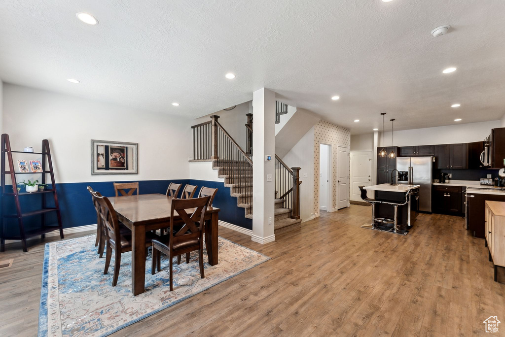 Dining area featuring stairway, baseboards, light wood-type flooring, recessed lighting, and a textured ceiling