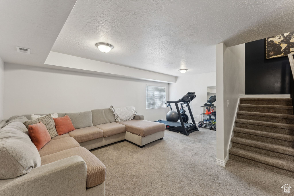 Living area featuring a textured ceiling, stairs, carpet flooring, and baseboards