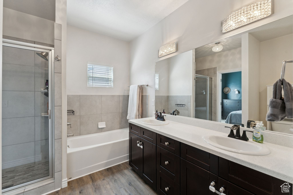 Ensuite bathroom featuring a shower stall, double vanity, wood finished floors, and a garden tub