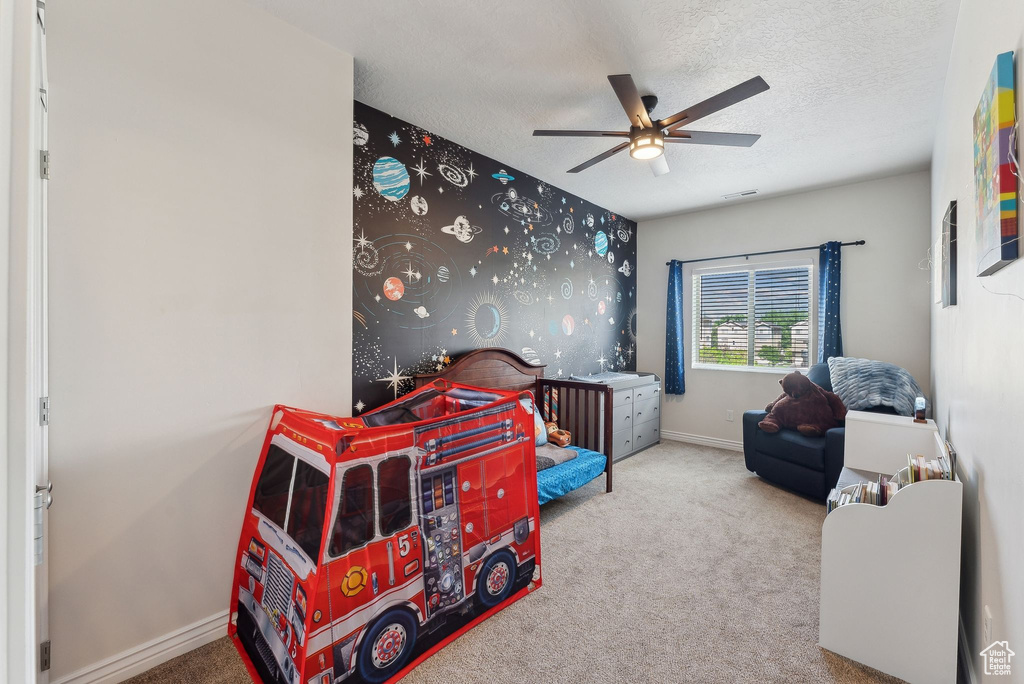 Carpeted bedroom featuring baseboards, a textured ceiling, and a ceiling fan