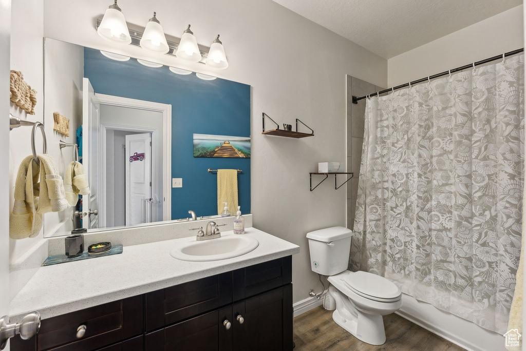 Bathroom featuring vanity, wood finished floors, toilet, and shower / bath combination with curtain
