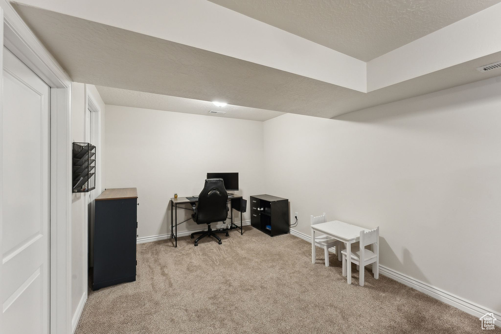 Carpeted office space with baseboards and a textured ceiling