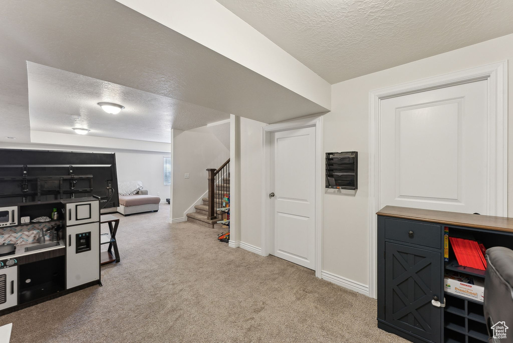 Kitchen with a textured ceiling, carpet floors, baseboards, and open floor plan