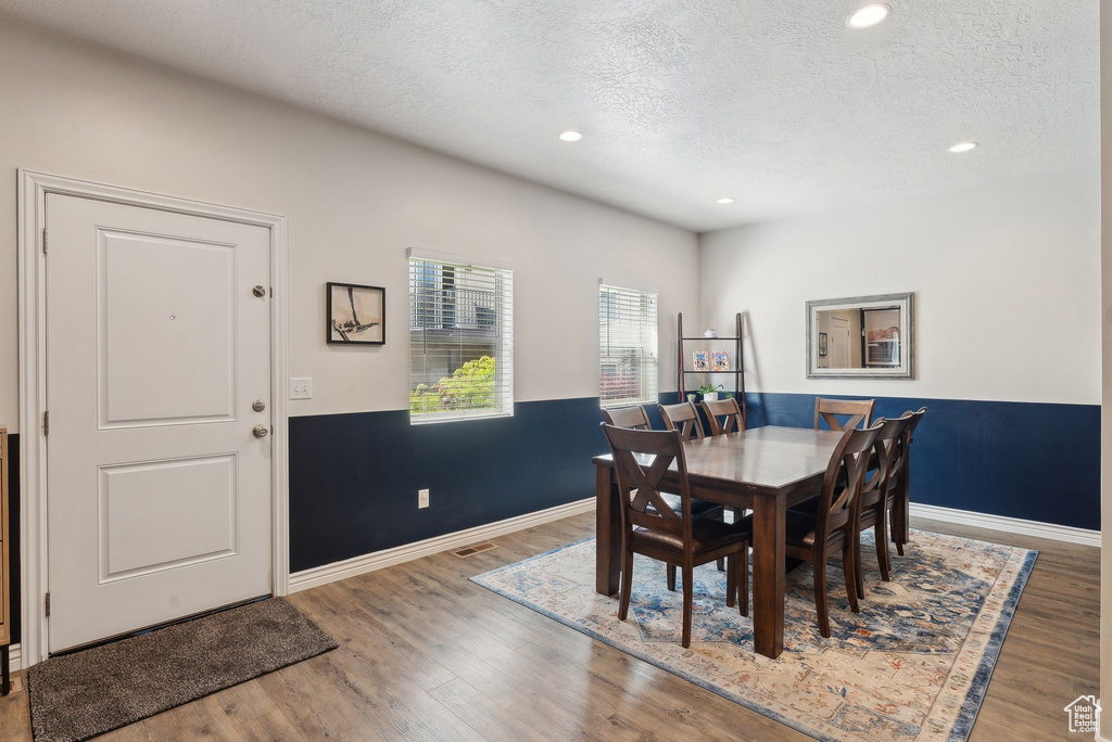 Dining room with a textured ceiling, wood finished floors, baseboards, and recessed lighting