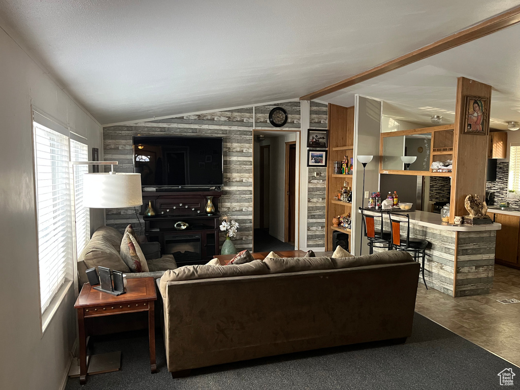 Living area featuring vaulted ceiling and a glass covered fireplace