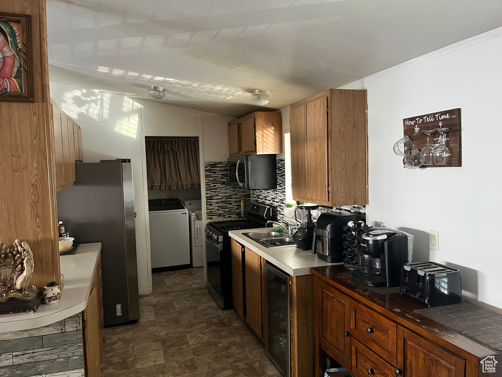 Kitchen featuring gas stove, washer and clothes dryer, beverage cooler, freestanding refrigerator, and vaulted ceiling
