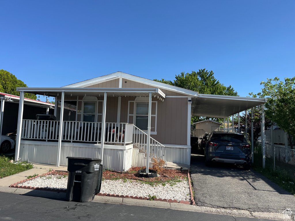 Manufactured / mobile home featuring covered porch, a carport, and driveway