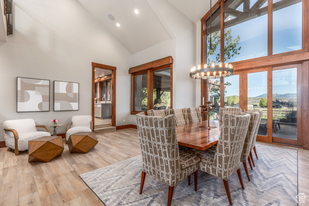 Dining room with high vaulted ceiling, wood finished floors, a chandelier, recessed lighting, and baseboards