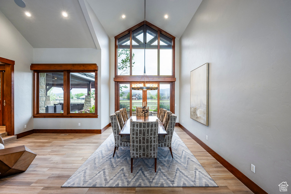 Dining room featuring high vaulted ceiling, light wood finished floors, a chandelier, baseboards, and recessed lighting