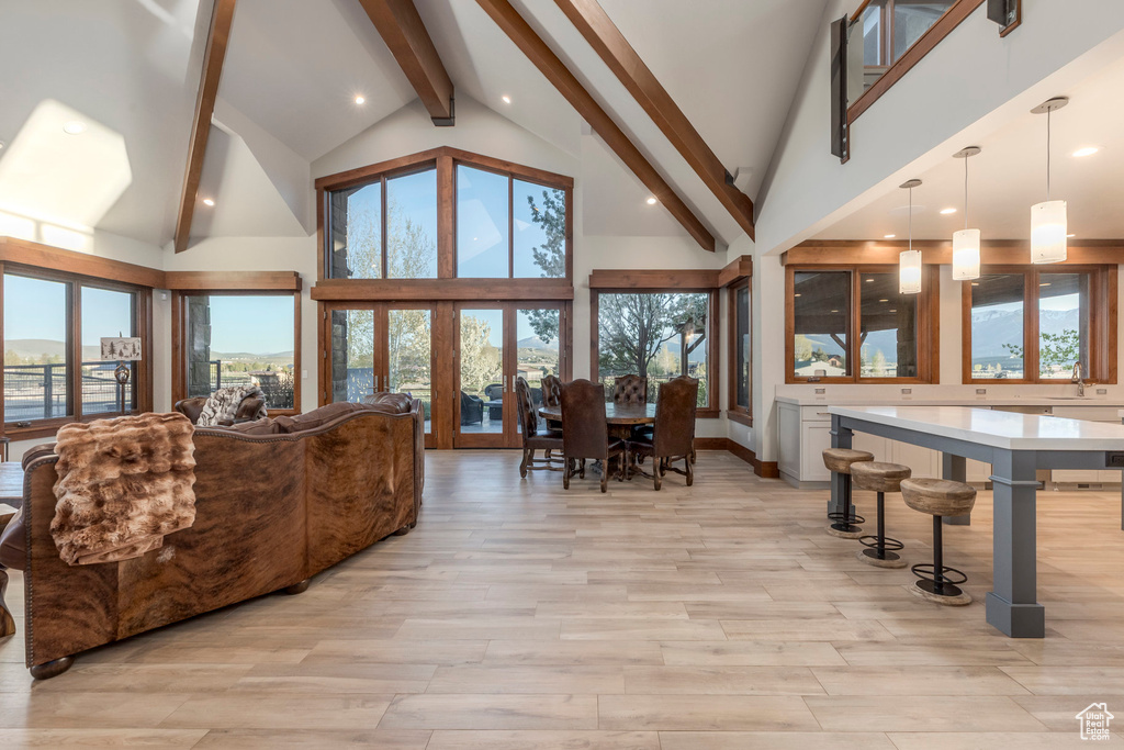 Living area featuring beamed ceiling, light wood-style floors, high vaulted ceiling, and plenty of natural light
