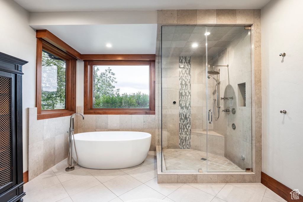 Full bath with a freestanding tub, a shower stall, tile walls, and tile patterned floors