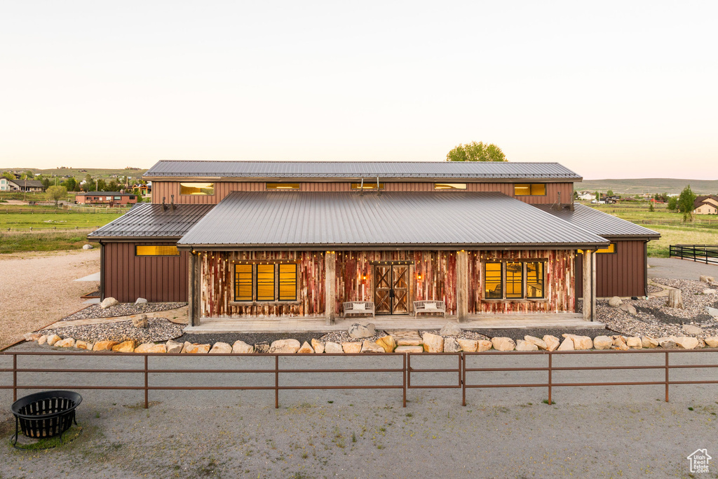 Back of house at dusk with board and batten siding, metal roof, and a porch